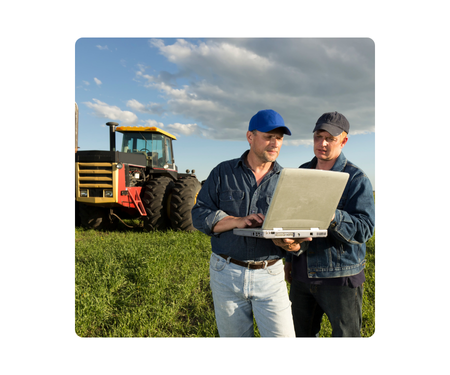 farmers using a rugged laptop, tractor in background