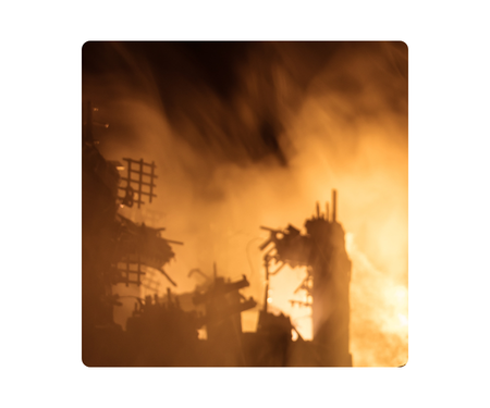 Silhouetted structures with jagged edges against orange flames and thick smoke.