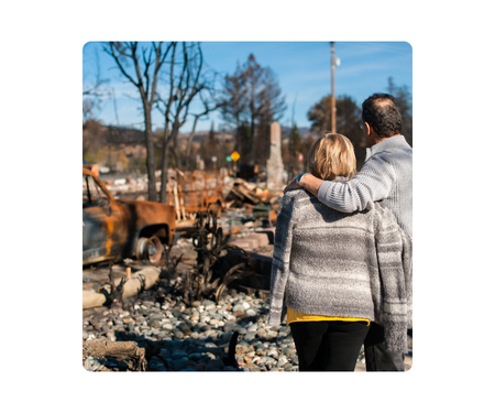 fema aa image - two people with backs turned to camera looking at storm damage