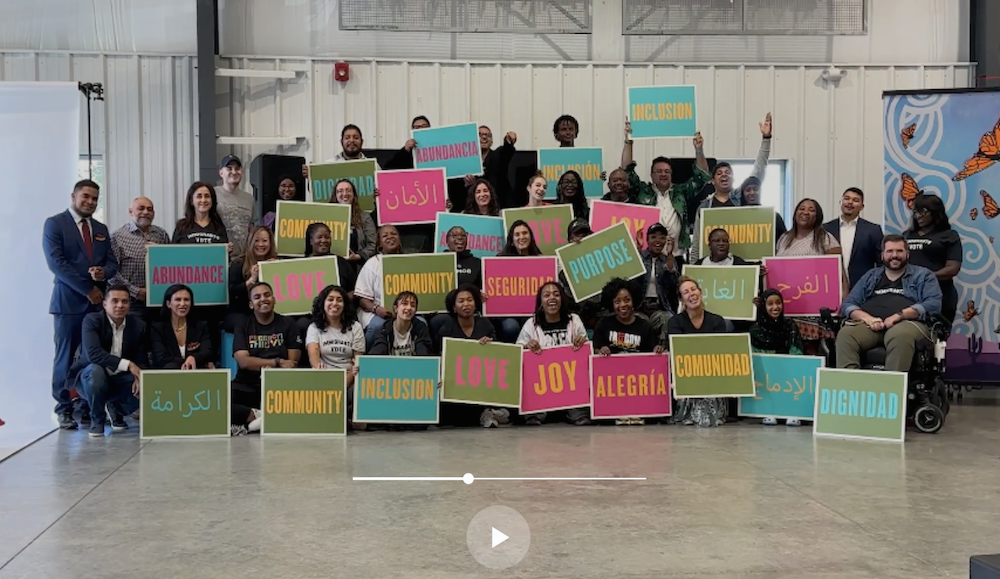 Video Still of Freedom to Thrive attendees in Nashville holding signs with words like love, community, inclusion and purpose that they chose to represent the freedom to thrive in this photo.