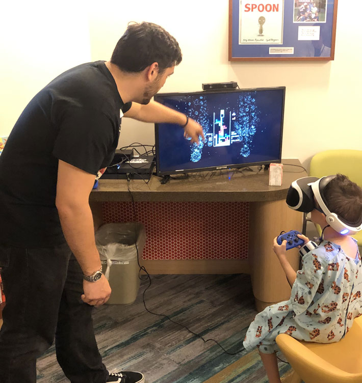 A photo of little boy and staff member playing video games.