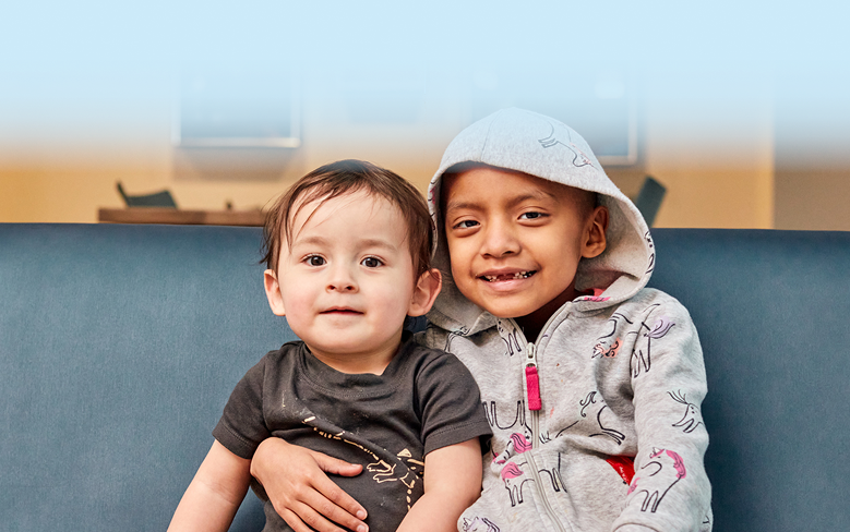 Two children sitting, hugging and smiling