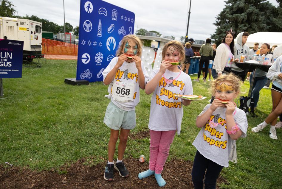Three girls eating watermelon outside.