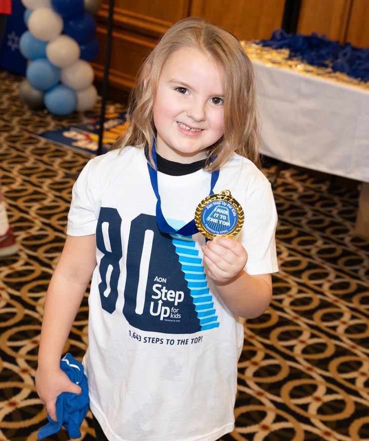 A photo of a young girl participant holding her medal.