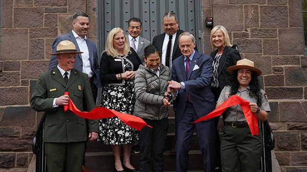 A group of people cutting red ribbon