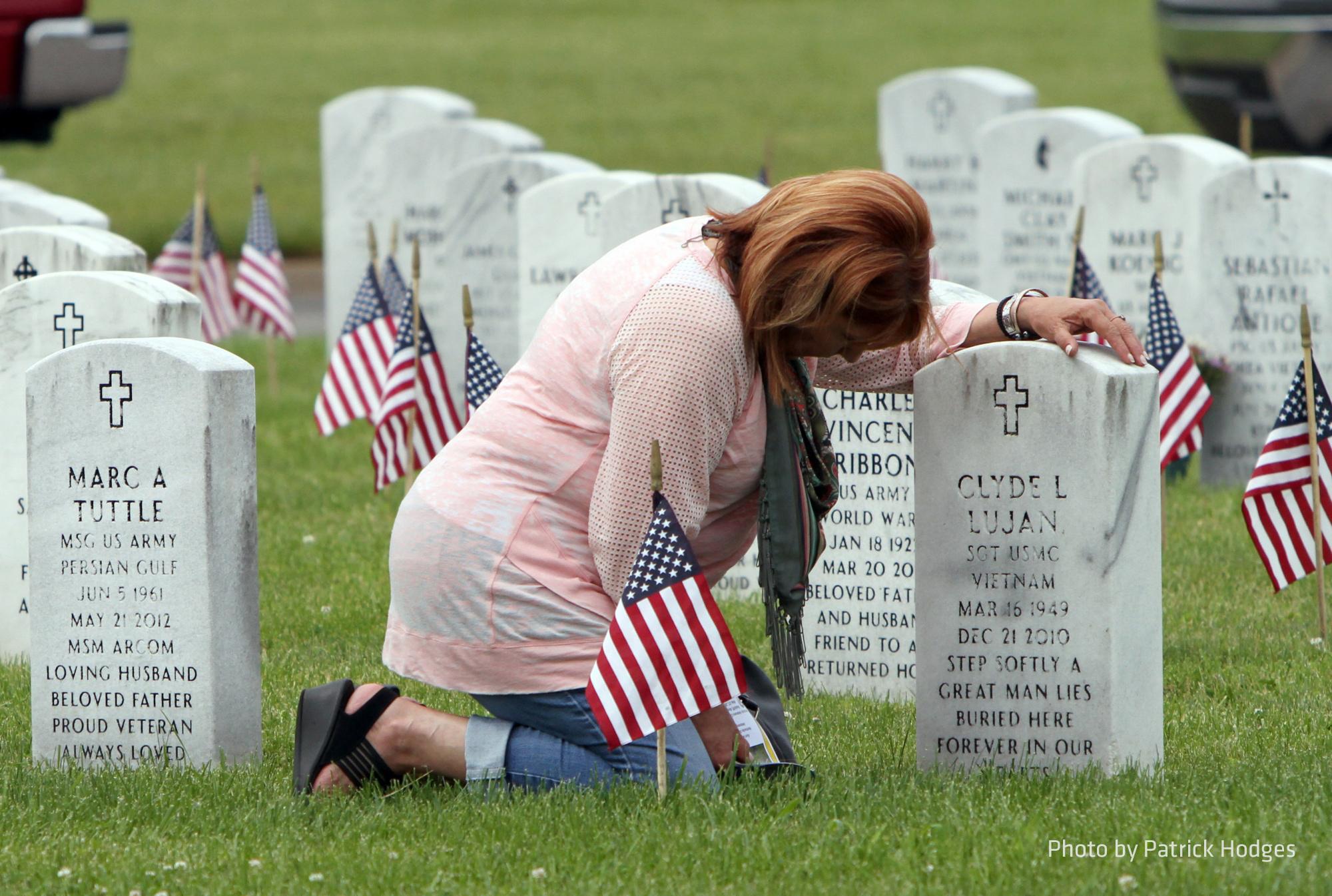Woman kneeling at graveside of fallen servicemenber