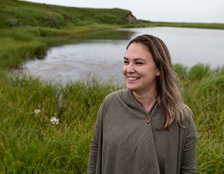Person smiling, standing in front of a pond