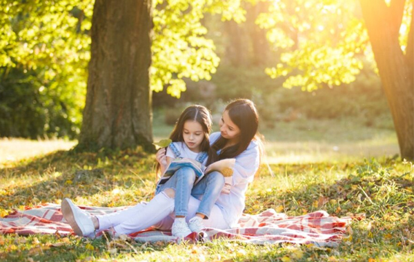 A parent reading to a child amongst trees