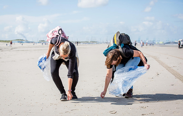 Two people cleaning up trash on a beach