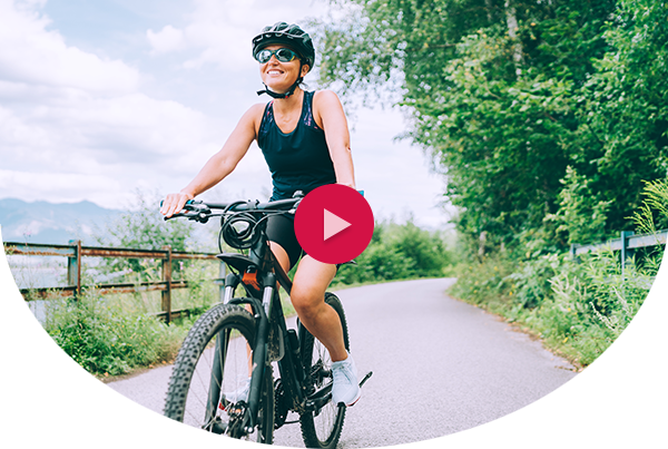 Woman biking amongst trees with mountains in the background