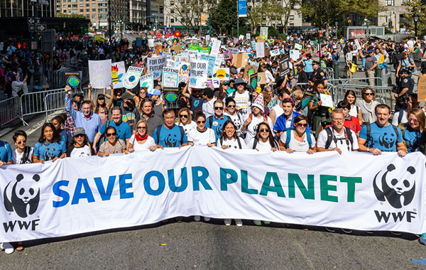 People standing together on a street and holding a sign that says, Save our planet