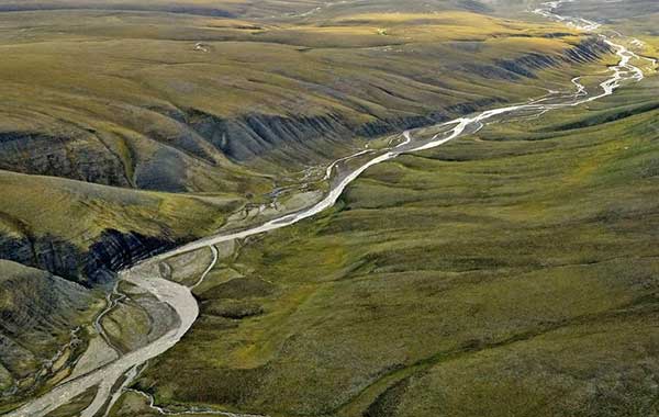 A narrow winding river surrounded by green hills