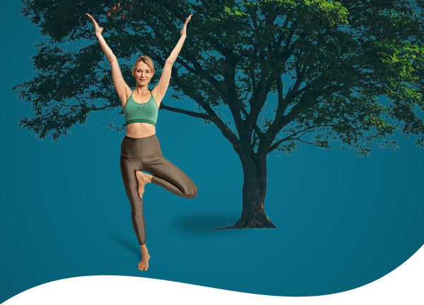 Person doing tree pose with tree in the background
