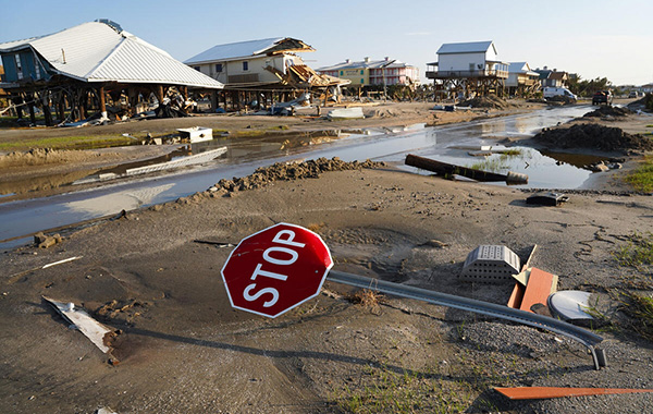 Flooded area with waters receding, bent stop sign, and houses in the distance