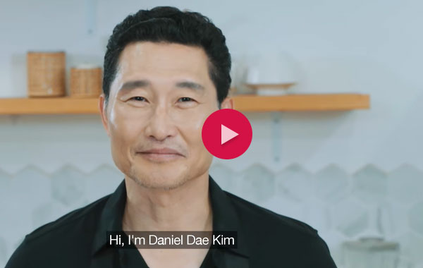 Daniel Dae Kim in a kitchen. The image has a red video play button - text below says 