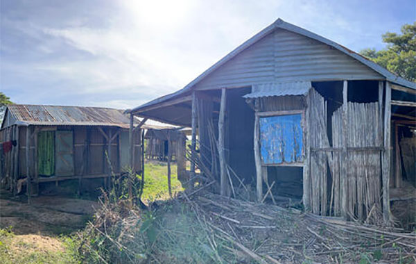 Wooden house in Madagascar with sun and trees peeking out behind it