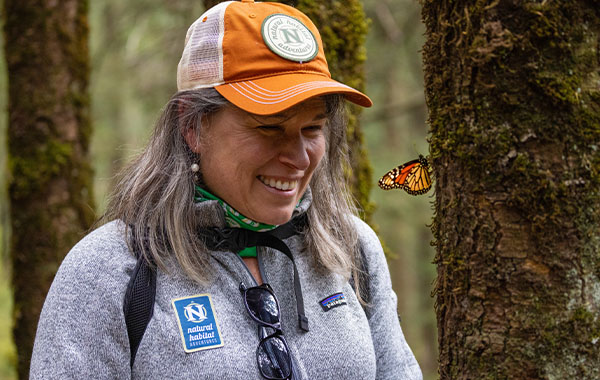 NatHab butterfly smiles as a monarch butterfly flies right in front of them