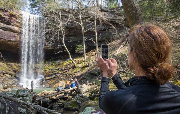 Someone using her smartphone to take a photo of a waterfall