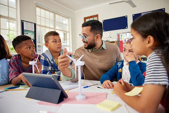 Educator teaching young students around a table