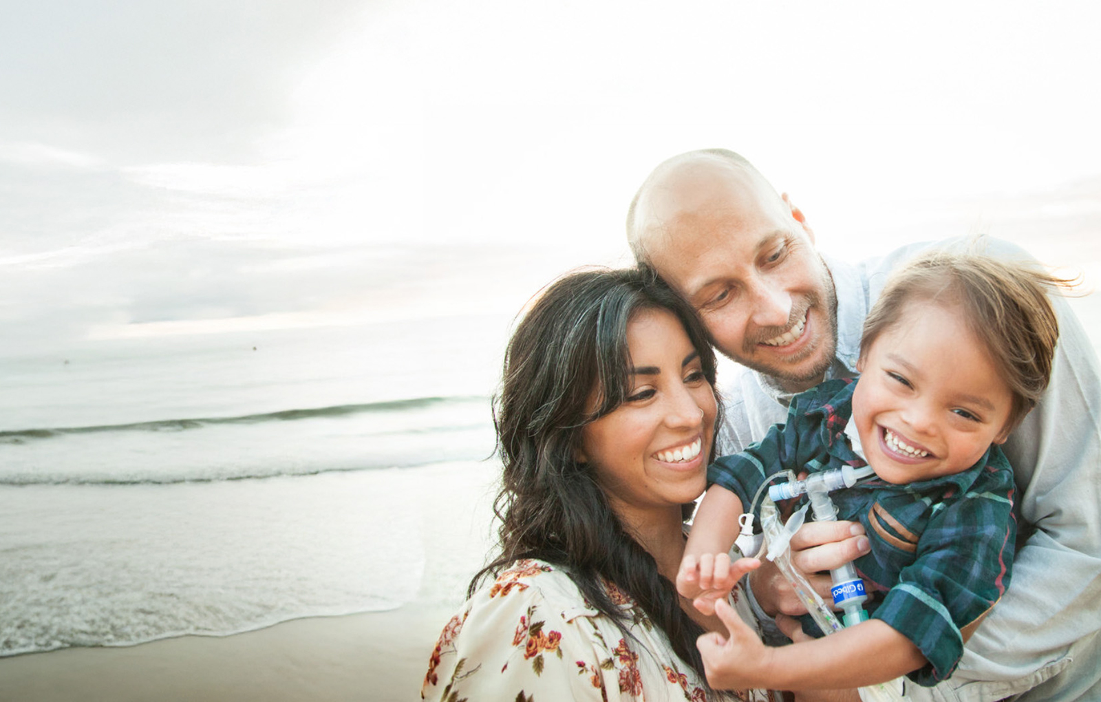 mom, dad and young boy smiling with beach background
