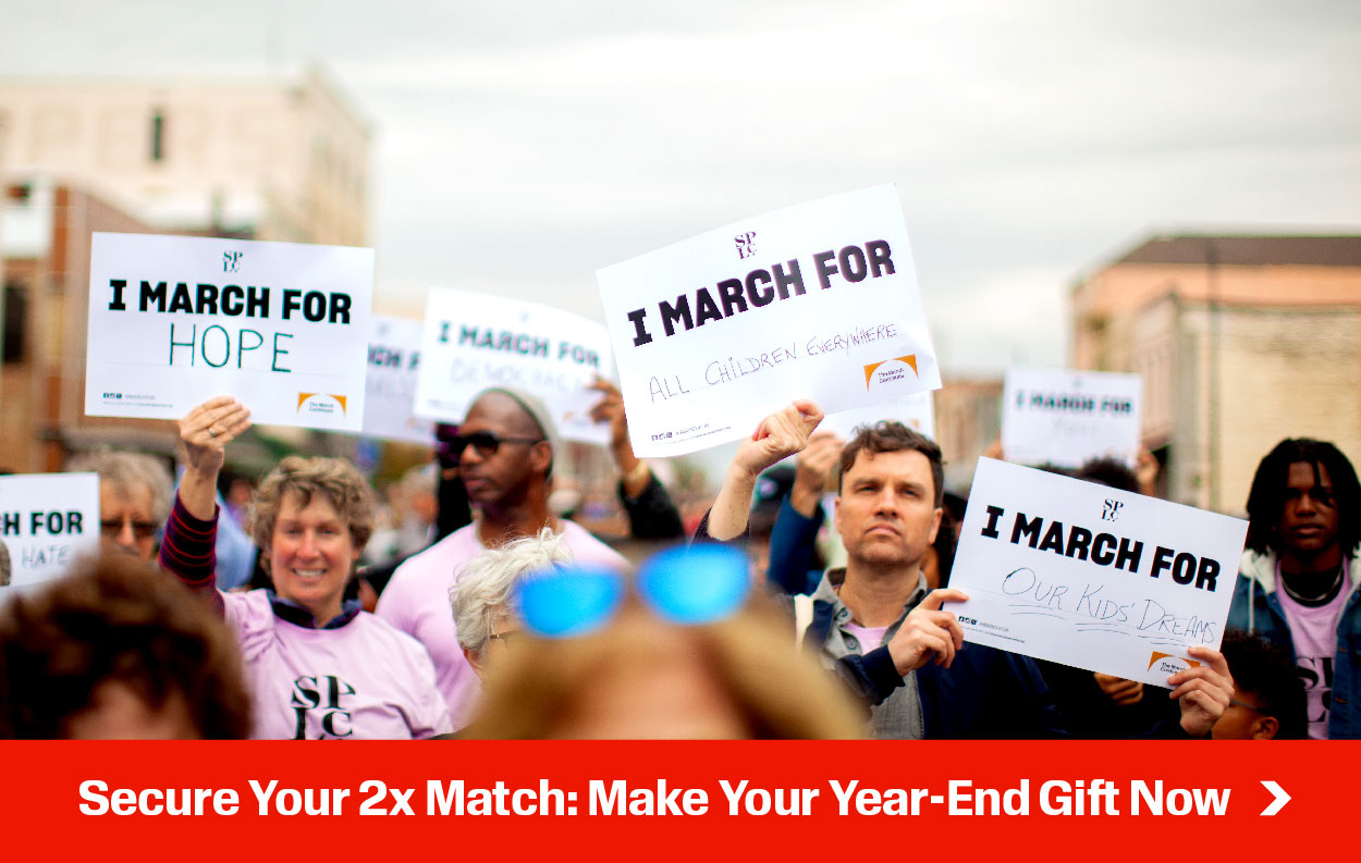 A marching group. Bold white lettering over a solid red background reads, 