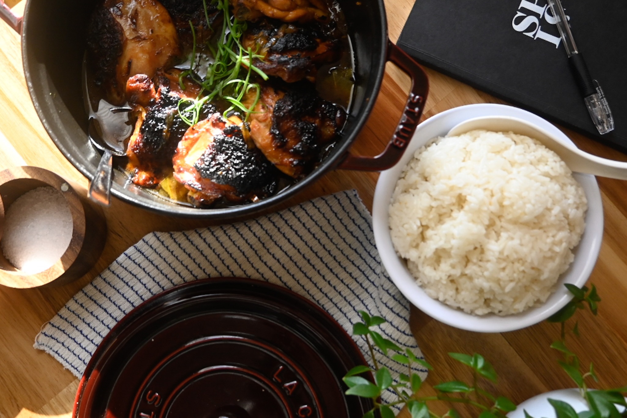 A pot of hearty chicken adobo next to a cup of steamed white rice