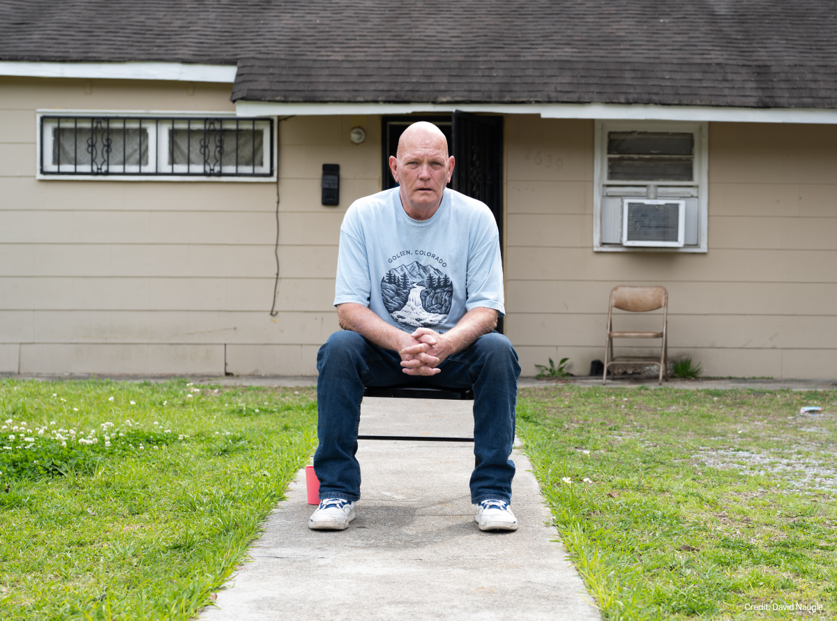 Andrew Sanders, 62, looks into the camera with hands, leaning forward, hands folded.