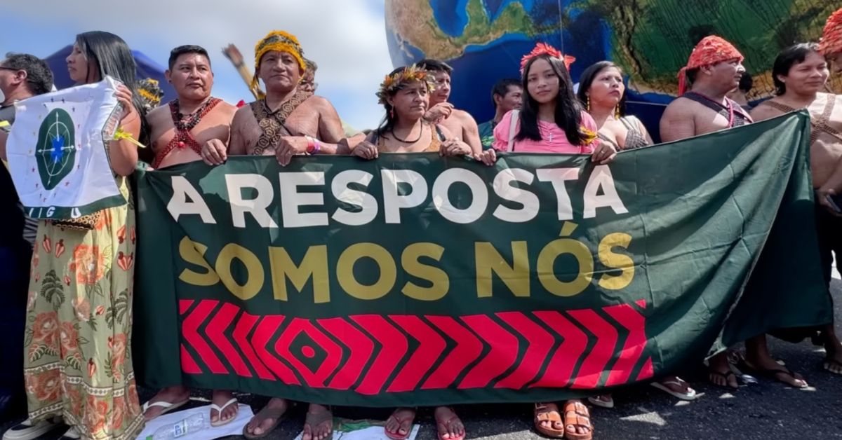 Indigenous leaders holding a large banner that reads 