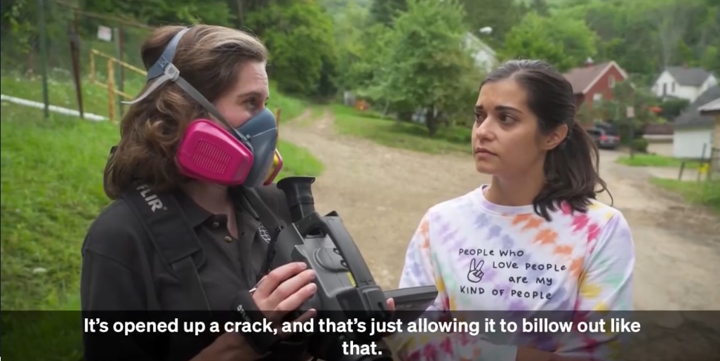 Earthworks staffer Melissa Ostroff wears a gas mask while talking with a resident of Bradford, Pennsylvania. Ostroff is telling her that a gas storage tank has opened up a crack and that's allowing invisible gas to billow out. 