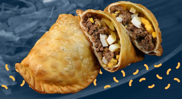An empanada cut in half is positioned on a blue plate.