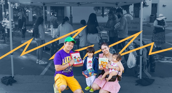 A family of 4 smiles and poses while holding up free books they recieved.