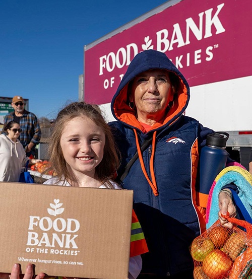 Woman and child holding box of food.