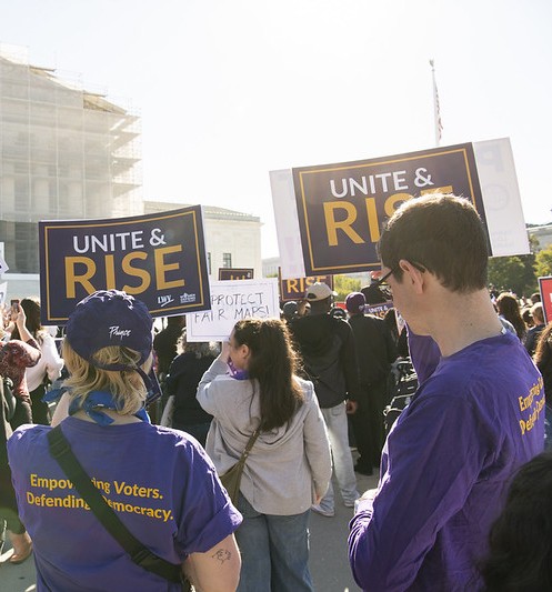 Two people holding Unite & Rise signs